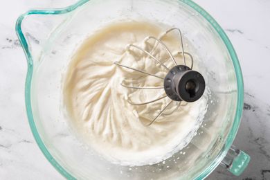 Whipped cream in a mixing bowl with a whisk attachment