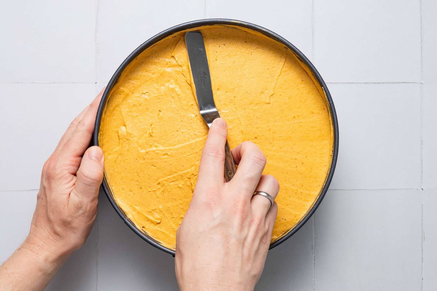Filling added to springform pan and smoothened using an off-set spatula for no-bake pumpkin cheesecake recipe