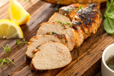 Grilled chicken breast halfway sliced on a cutting board