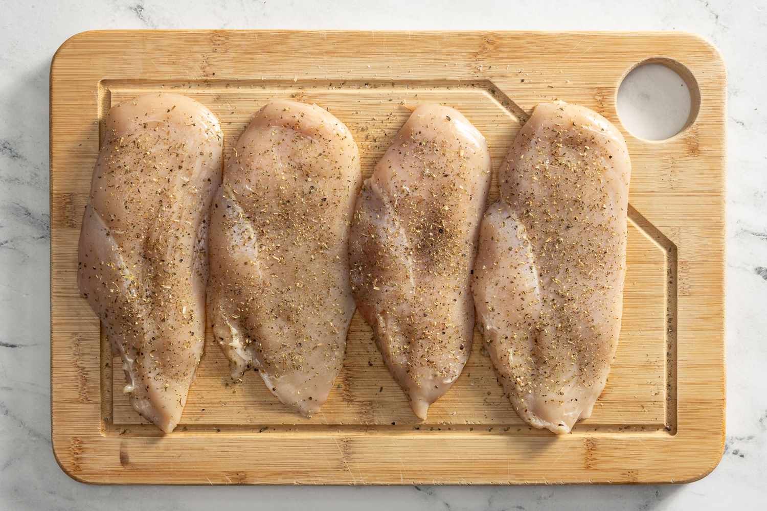 seasoned chicken cutlets on a cutting board for creamy tuscan chicken recipe