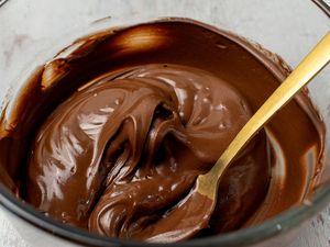 Melted chocolate in a bowl with a gold spoon creamy consistency for baking or cooking