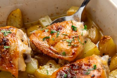 Garlic butter chicken with potatoes garnished with herbs in a tray