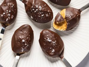 Closeup overhead shot of spoons with chocoalte and sea salt covered peanut butter, with a bite take out of one of the spoons