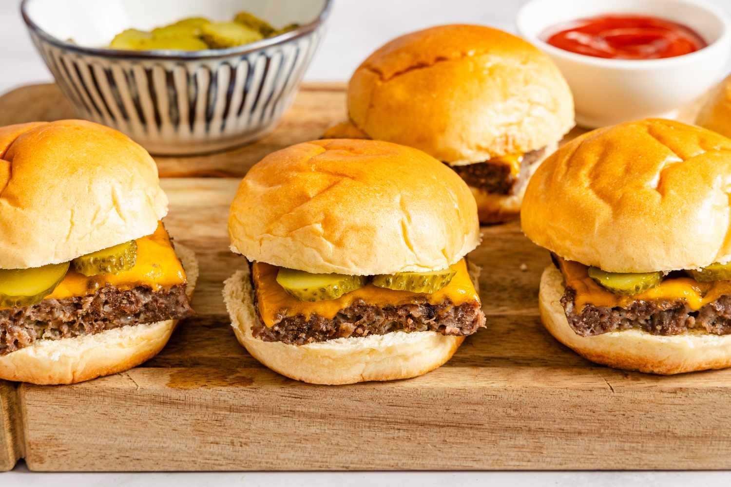 Mini cheeseburger sliders with pickles on a wooden board