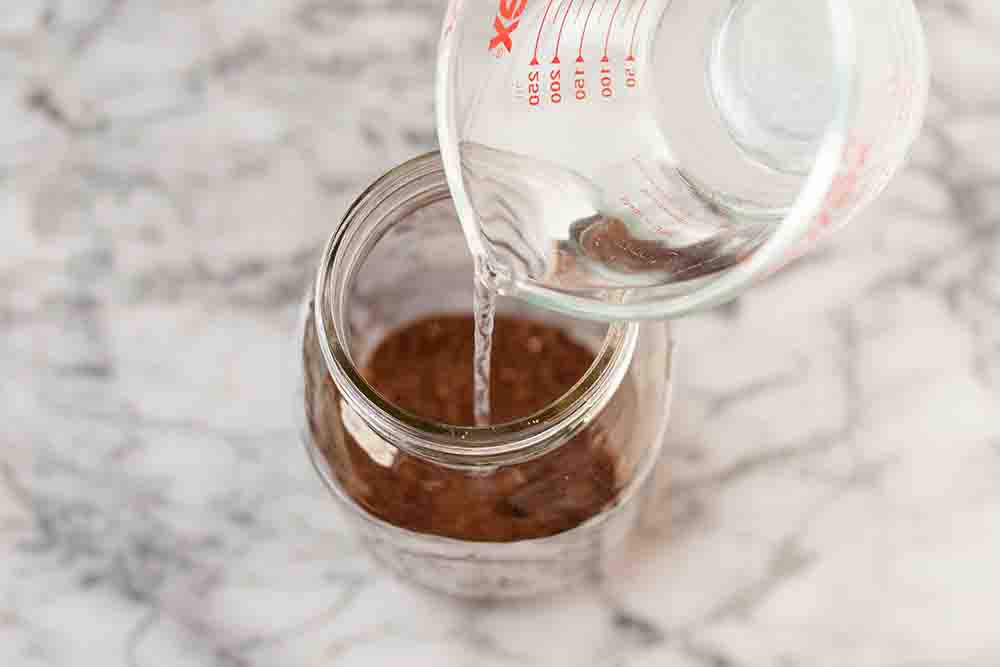 Water being poured into the jar holding the coffee grounds 