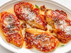Chicken saltimbocca plated topped with crispy prosciutto and grated cheese