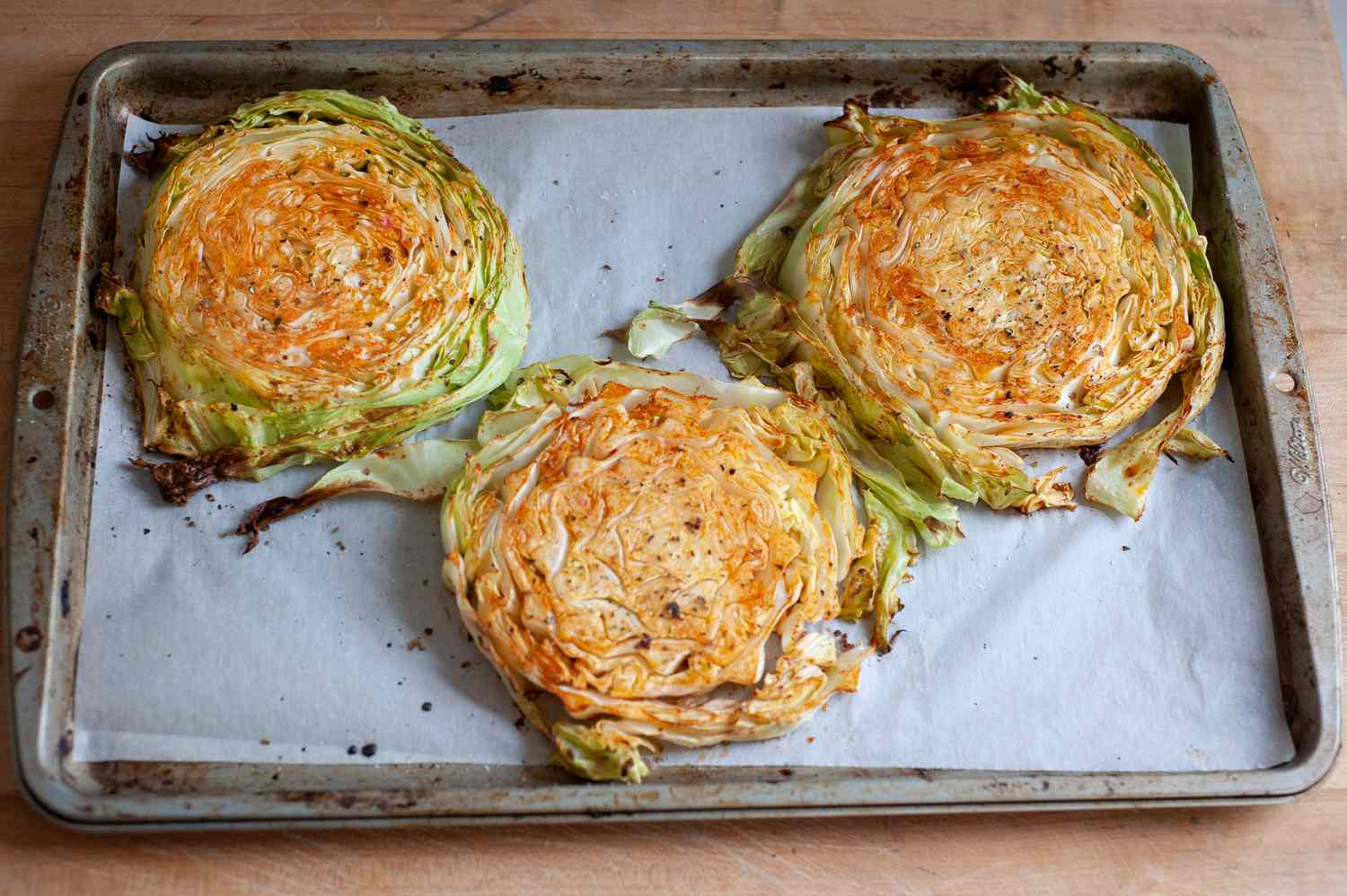 Roasted cabbage steaks on a baking sheet.
