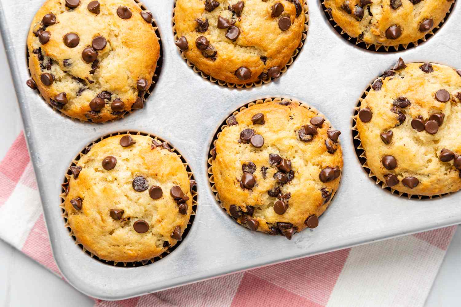 Banana Chocolate Chip Muffins in a Baking Tray Over a Kitchen Towel