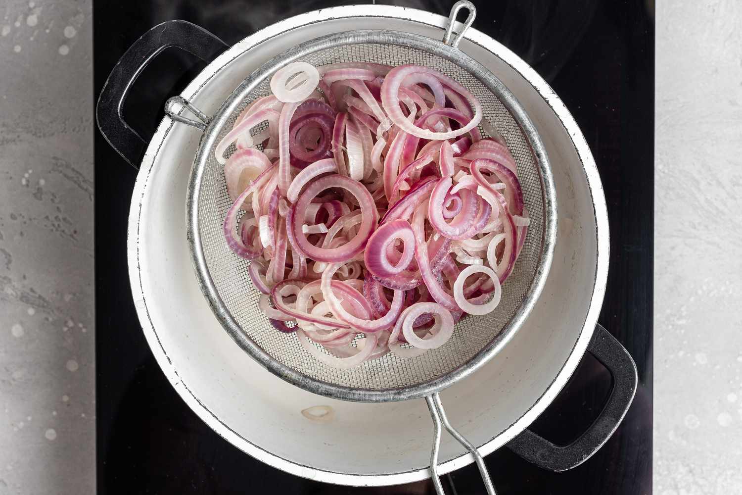 Draining blanched onions to make a pickled red onion recipe.