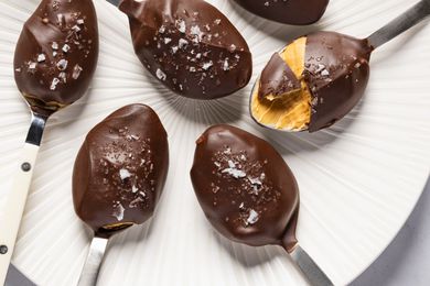 Closeup overhead shot of spoons with chocoalte and sea salt covered peanut butter, with a bite take out of one of the spoons