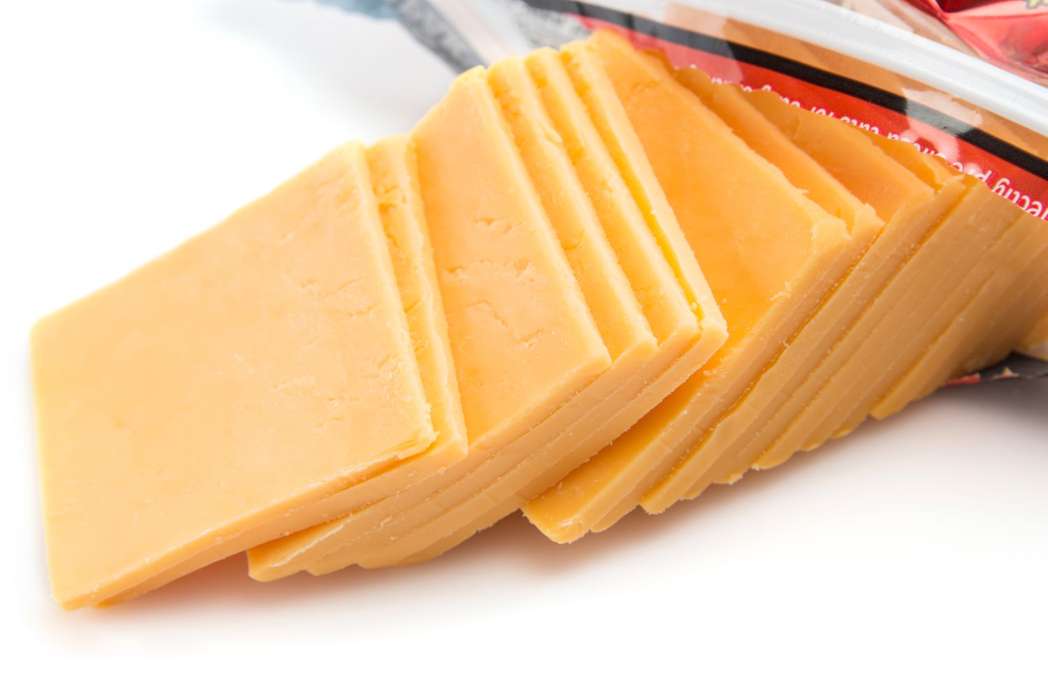 Slices of orange cheddar cheese coming out of an open package