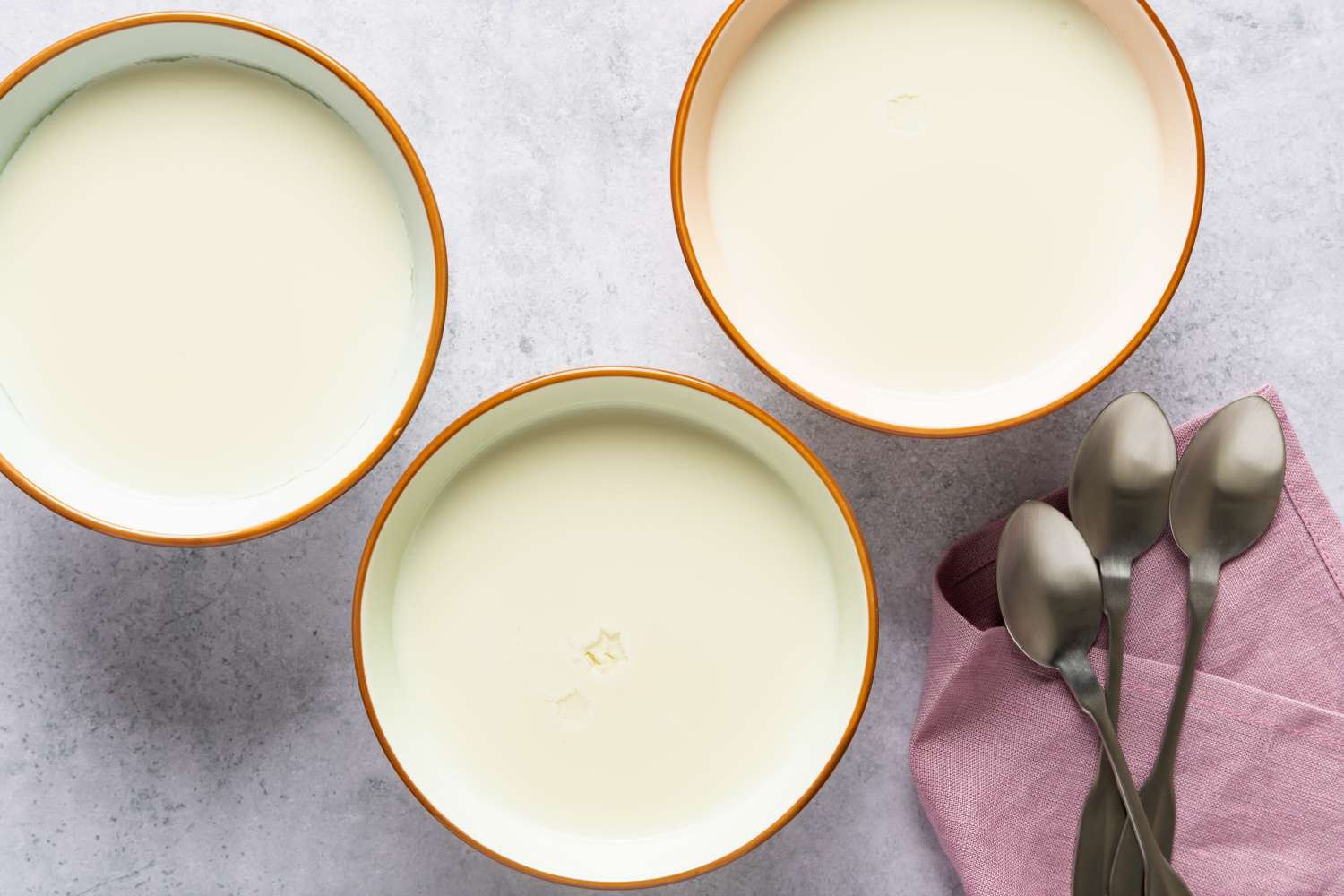 Three bowls of ginger milk pudding with spoons on the side