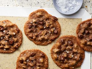 Chocolate chip cookies on a baking mat with a dish of salt nearby