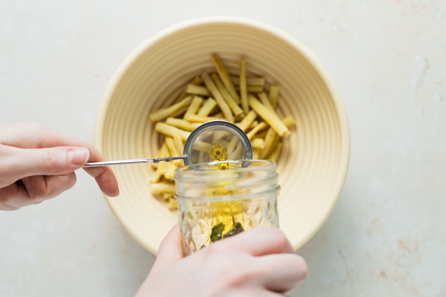 Adding dressing to a bowl of yellow beans.