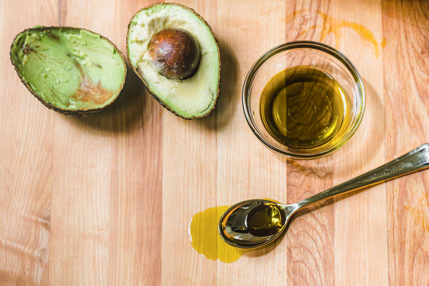 Avocado next to bowl of avocado oil