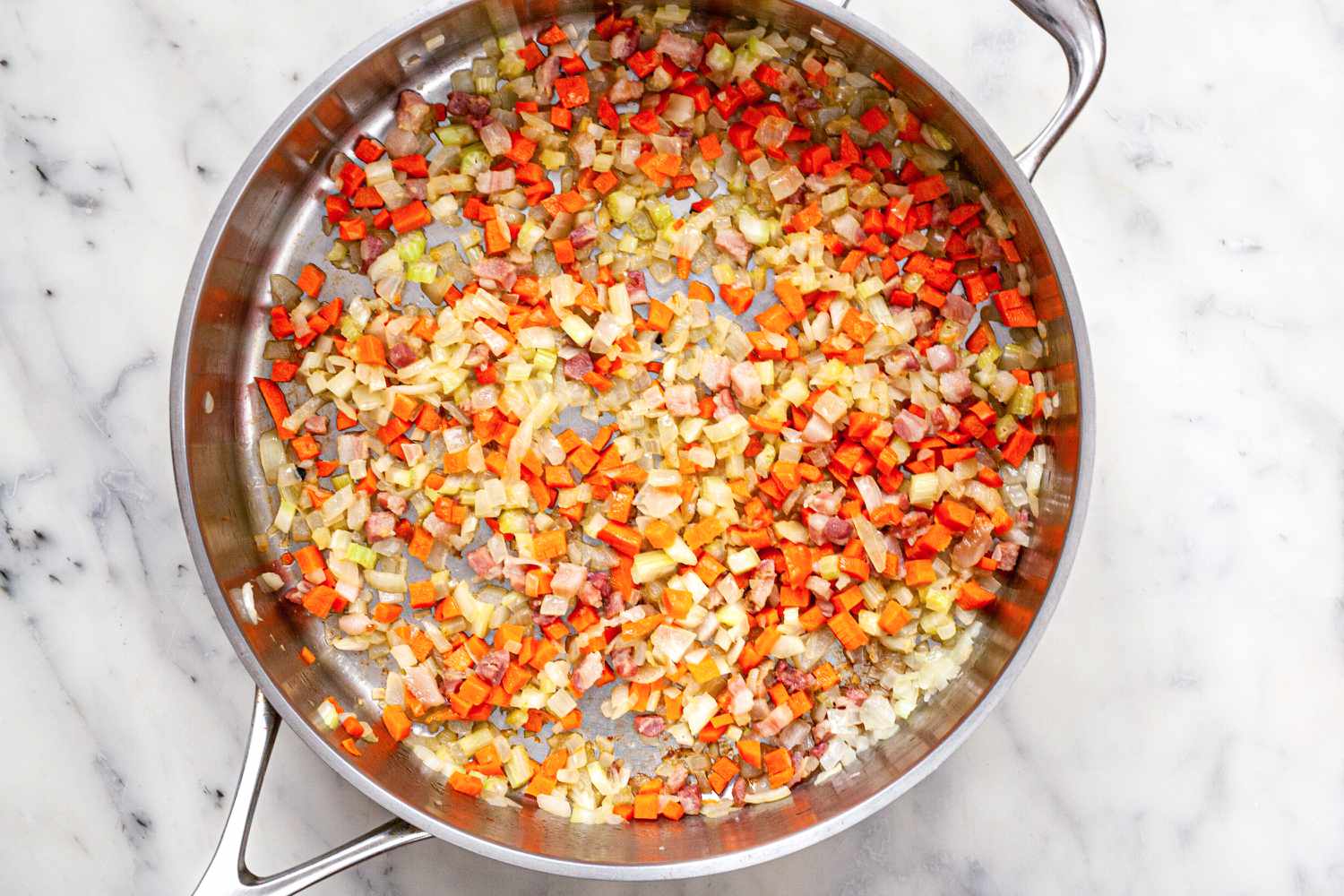 A skillet of onions and red peppers to make bolognese sauce.