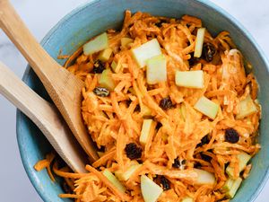Classic Carrot Salad in a bowl with wooden serving spoons.