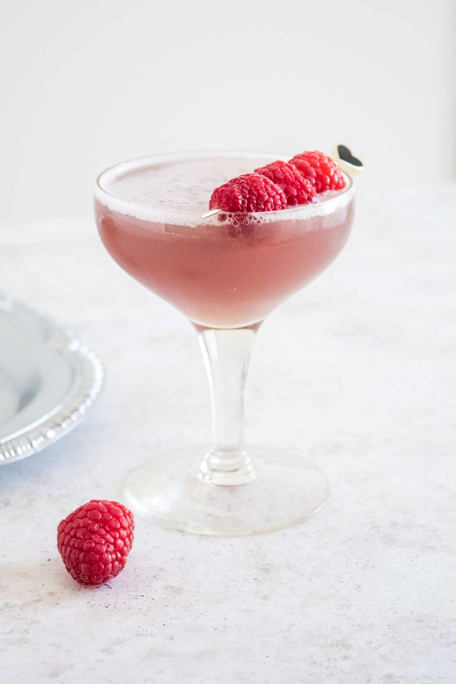 French Martini in a Glass Garnished with Raspberries Next to a Single Raspberry