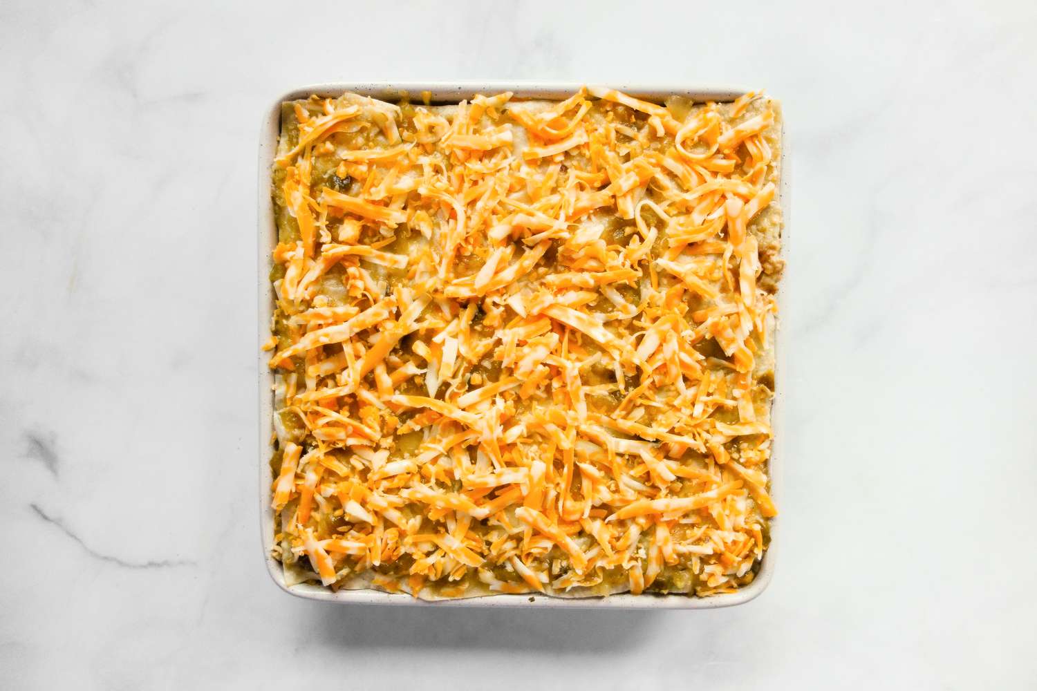 Assembled burrito casserole in baking dish.