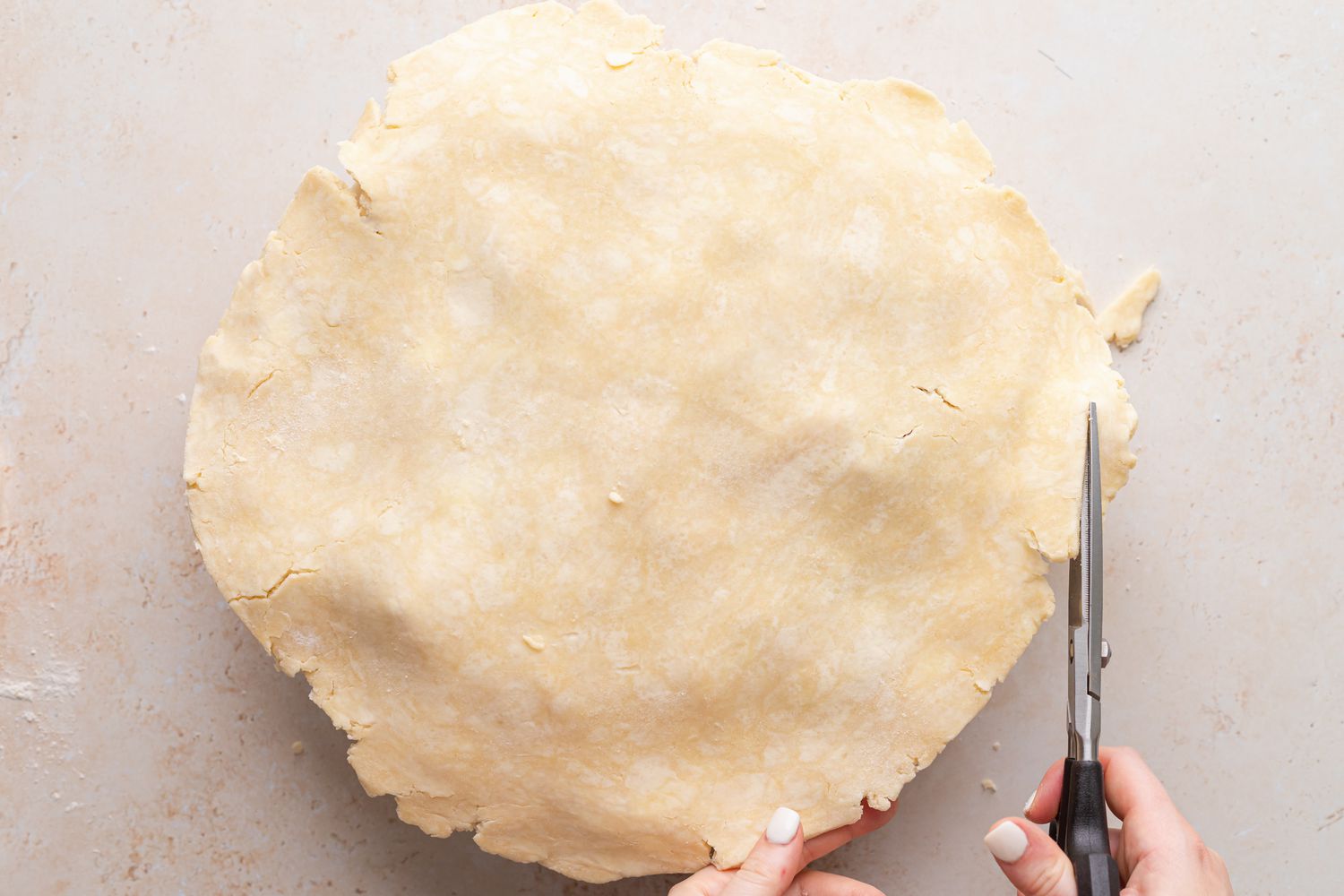 Trimming the top crust of an easy peach raspberry pie.