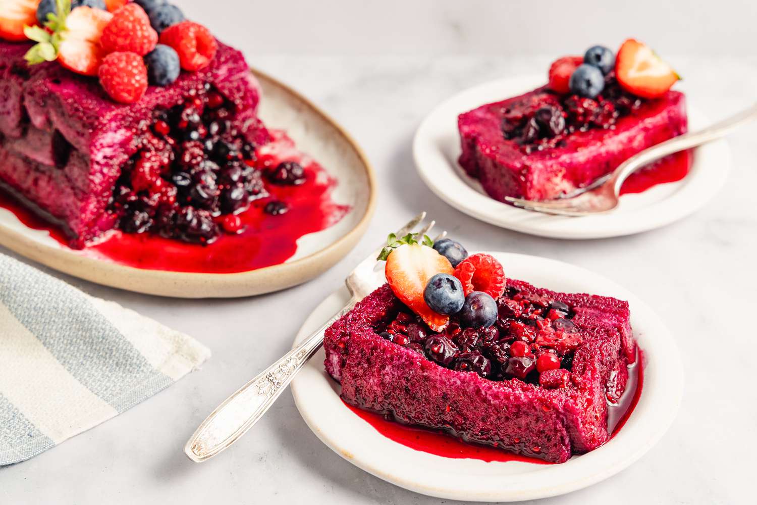 Slices of summer pudding with mixed berries and sauce on plates