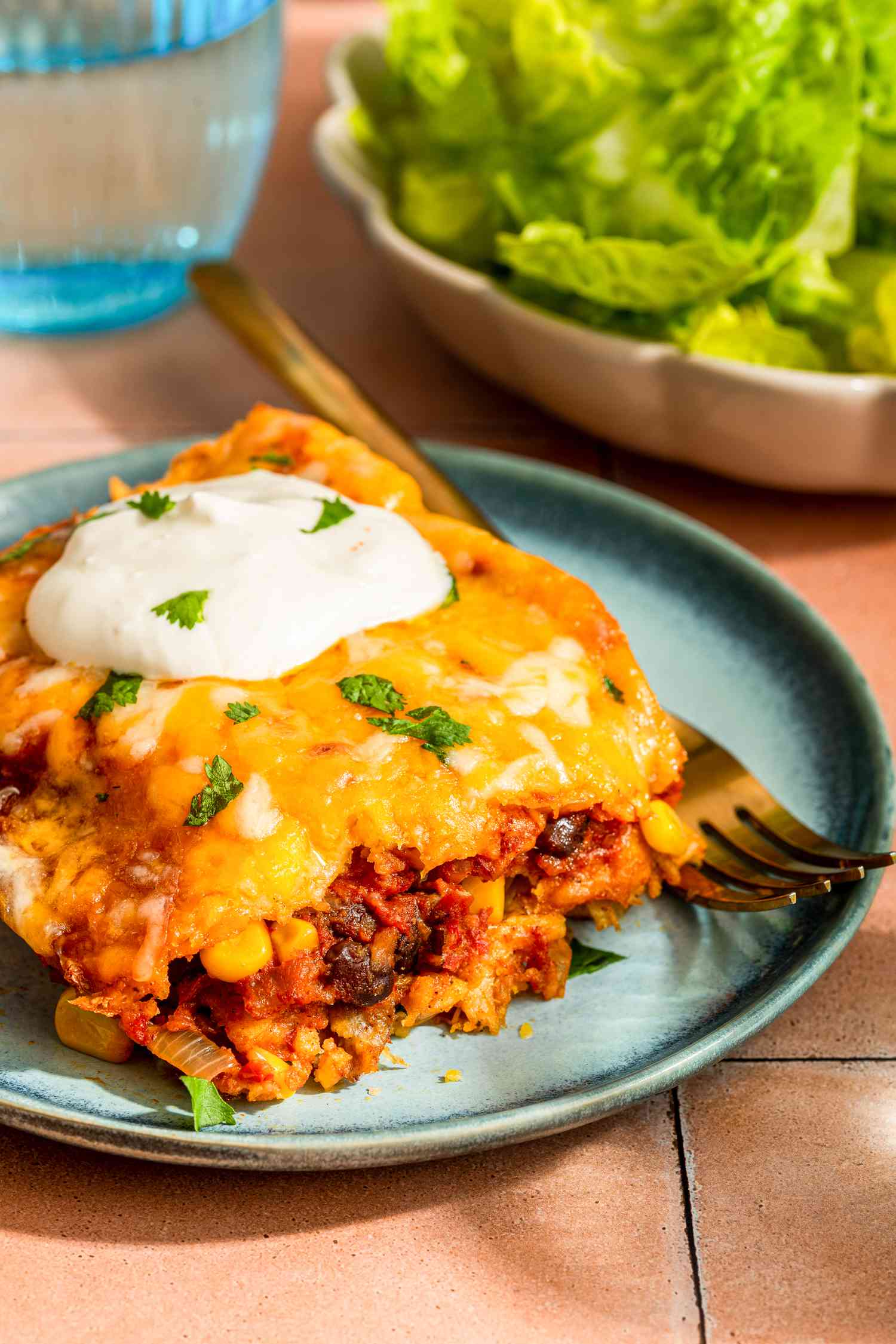 Serving of chicken taco casserole on a plate topped with a dollop of sour cream