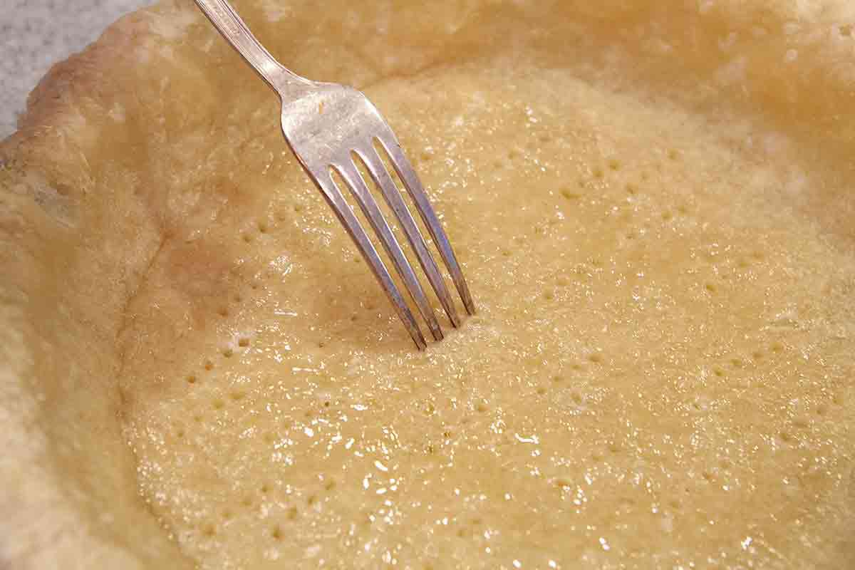 prick the bottom of the half baked pie crust with the tines of a fork