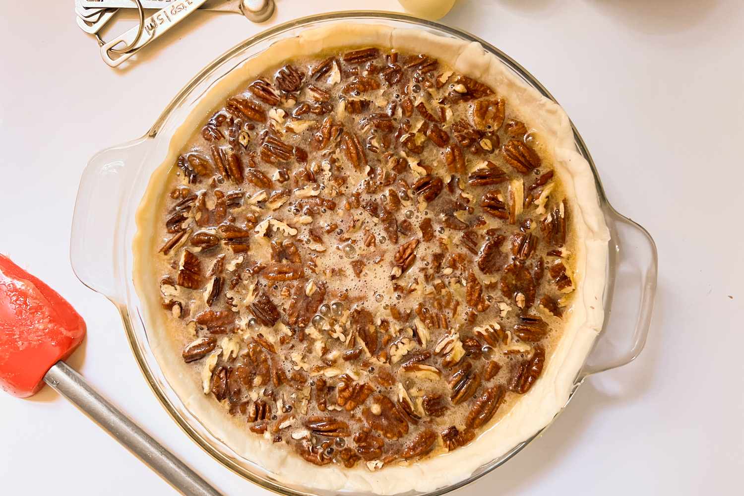 A pecan pie in a glass pie dish on a kitchen counter