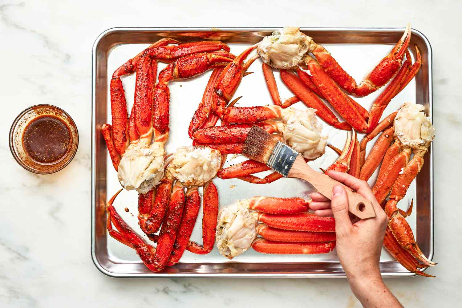 Seasoned Oil Brushed Onto the Crab Clusters on the Baking Sheet and on the Counter Next to the Tray, a Bowl of Seasoned Oil