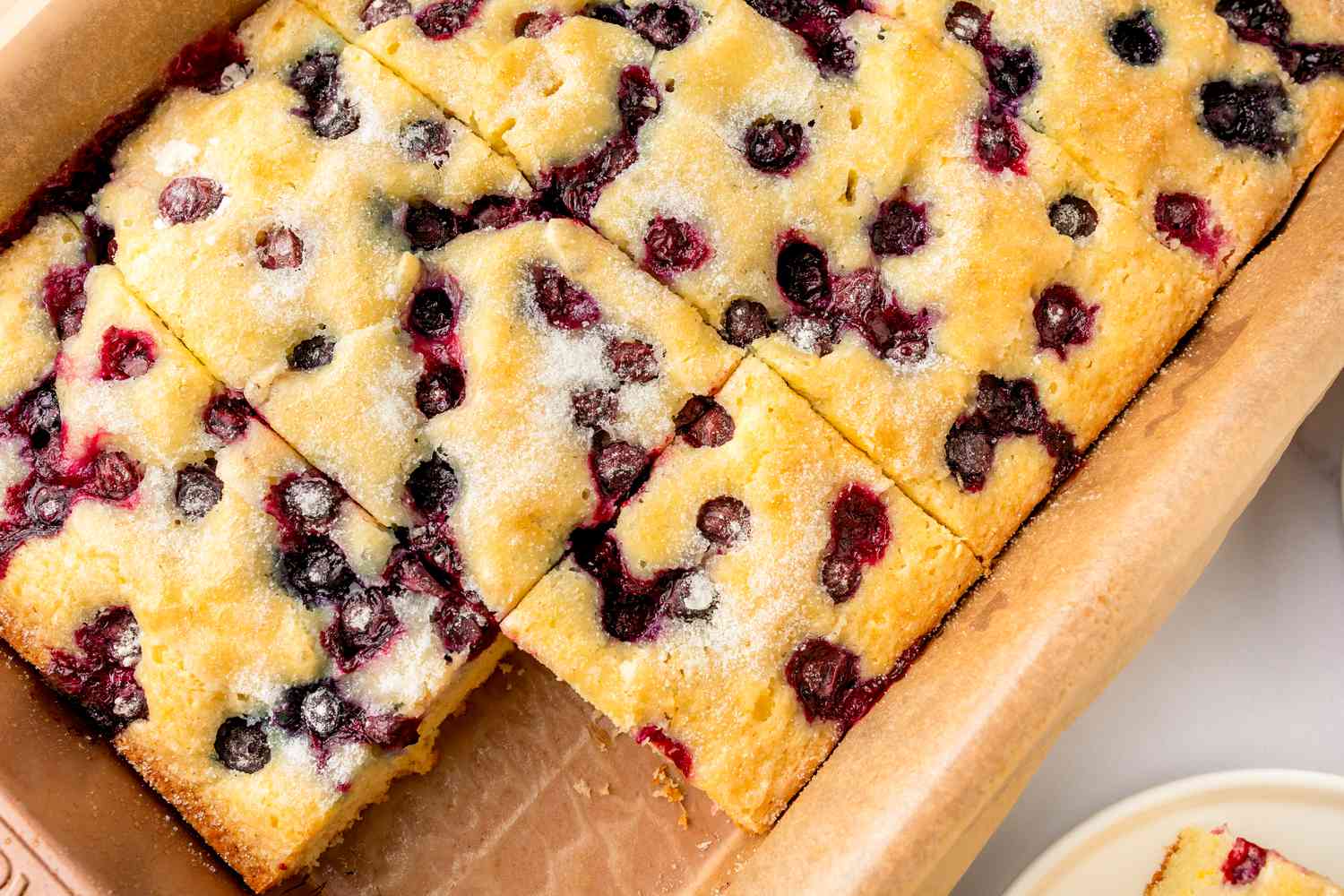 Blueberry sheet cake cut into pieces in a baking dish