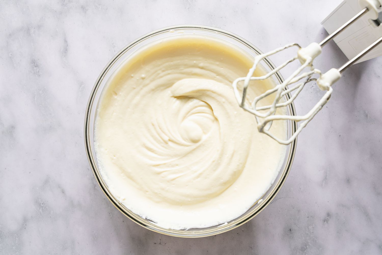 A bowl of whipped ricotta and egg mixture for Italian love cake recipe, with a hand mixer next to it