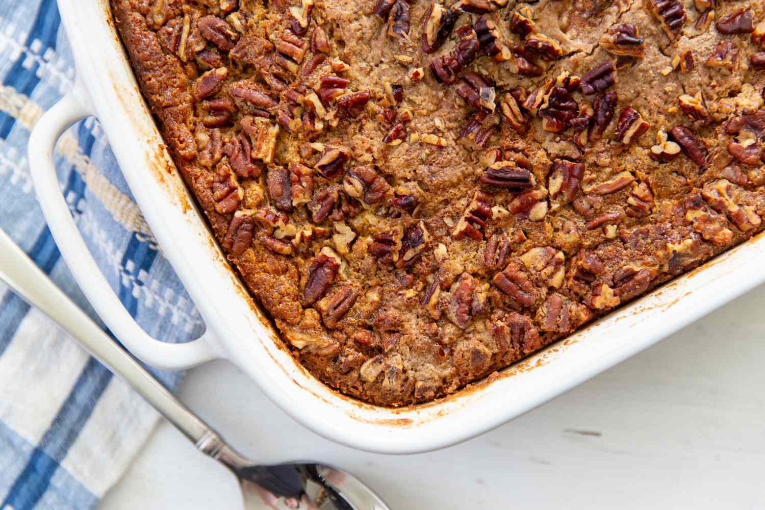 baking dish with cooked Pumpkin Dump Cake, spoon, and kitchen towel