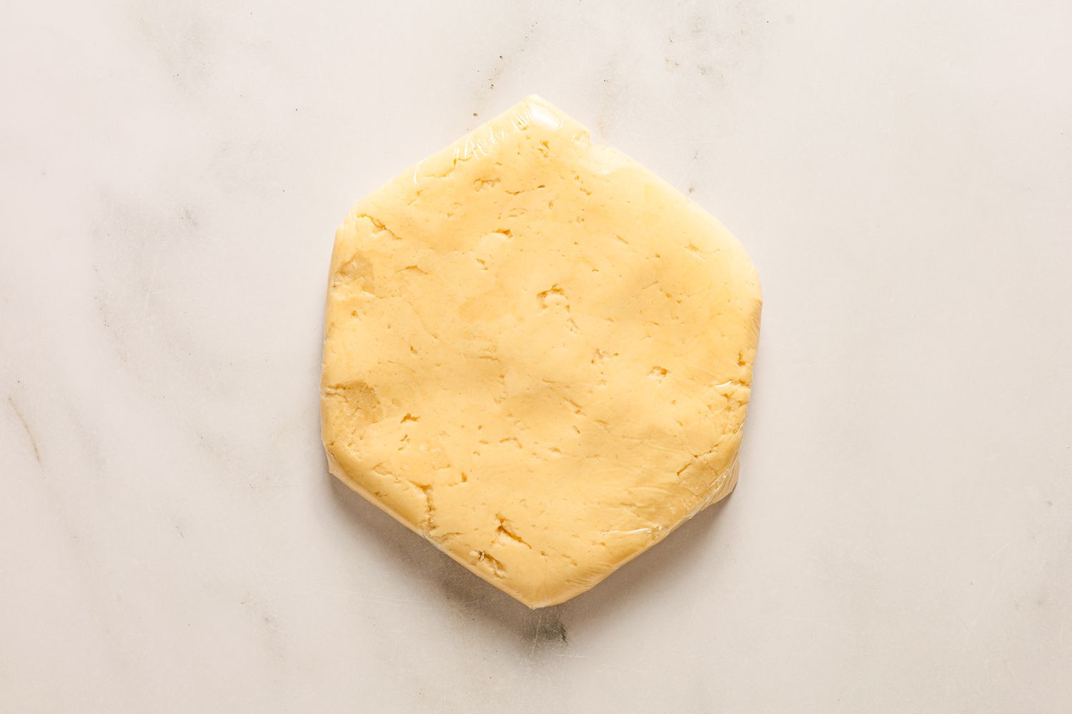 Overhead view of the dough wrapped in plastic wrap for chilling from Sand Tarts recipe