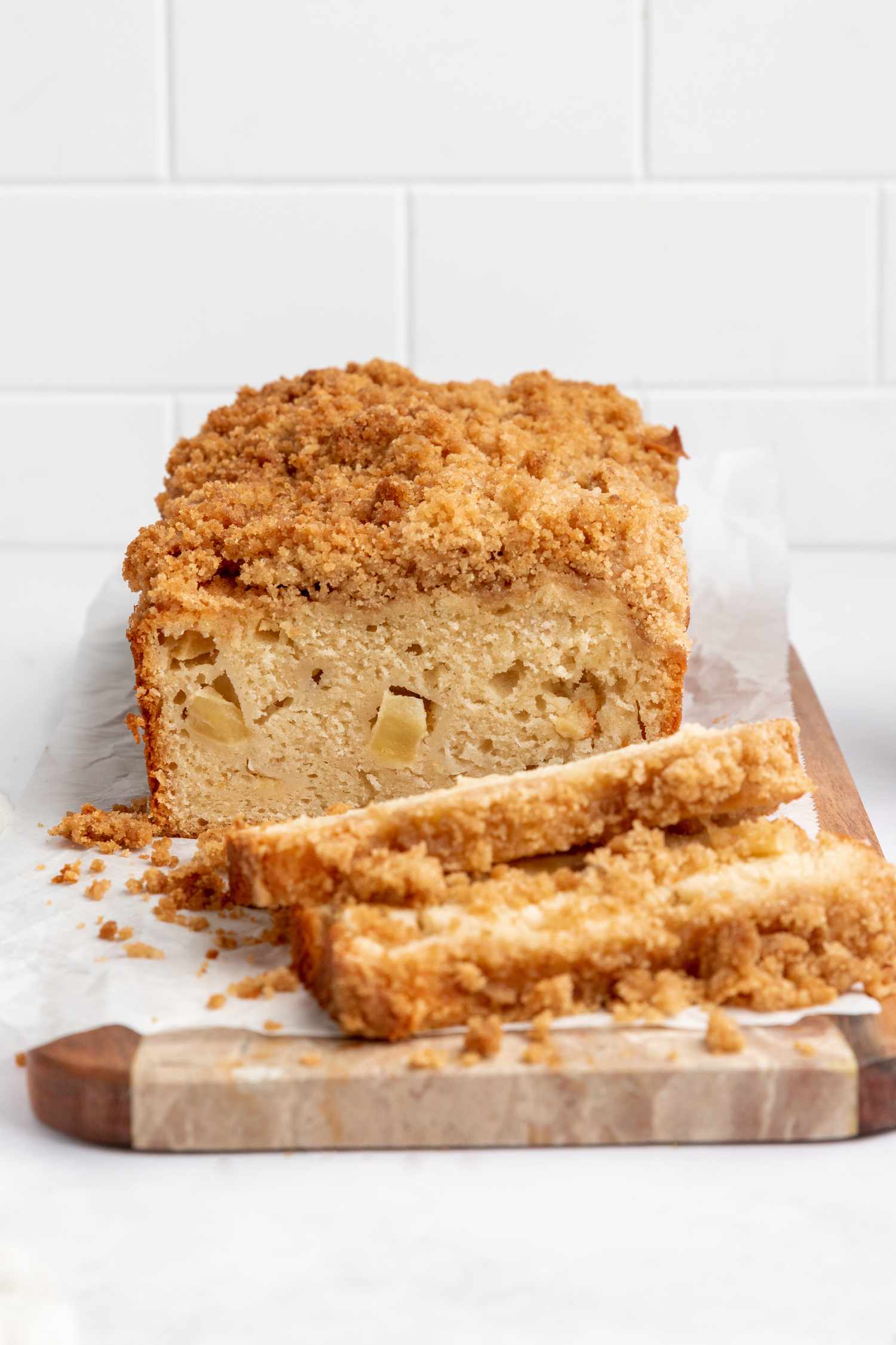 A loaf of homemade apple bread with a few slices cut and laid in front of the loaf.