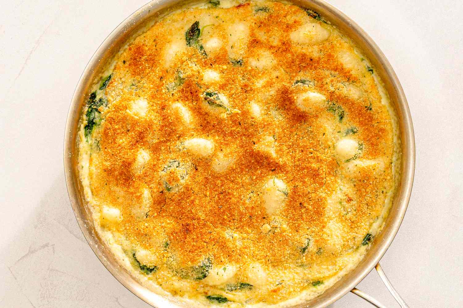 Creamy gnocchi dish baked with spinach and a golden crust in a skillet