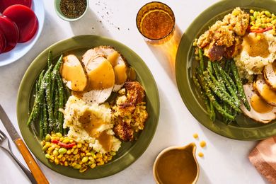 Plates with turkey green beans mashed potatoes corn and gravy seen from above