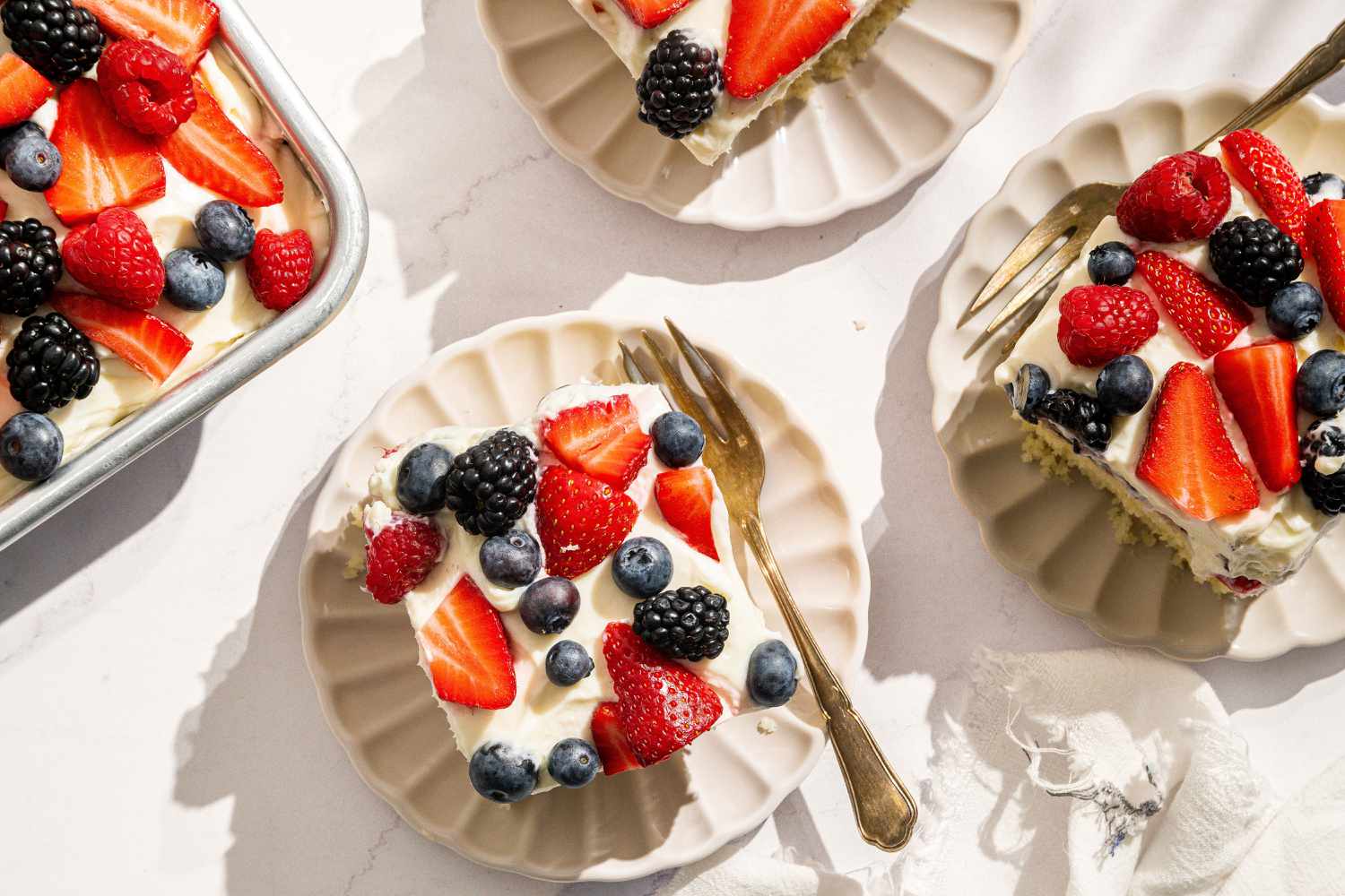 slices of Easy Berry Chantilly Cake on small plates with forks