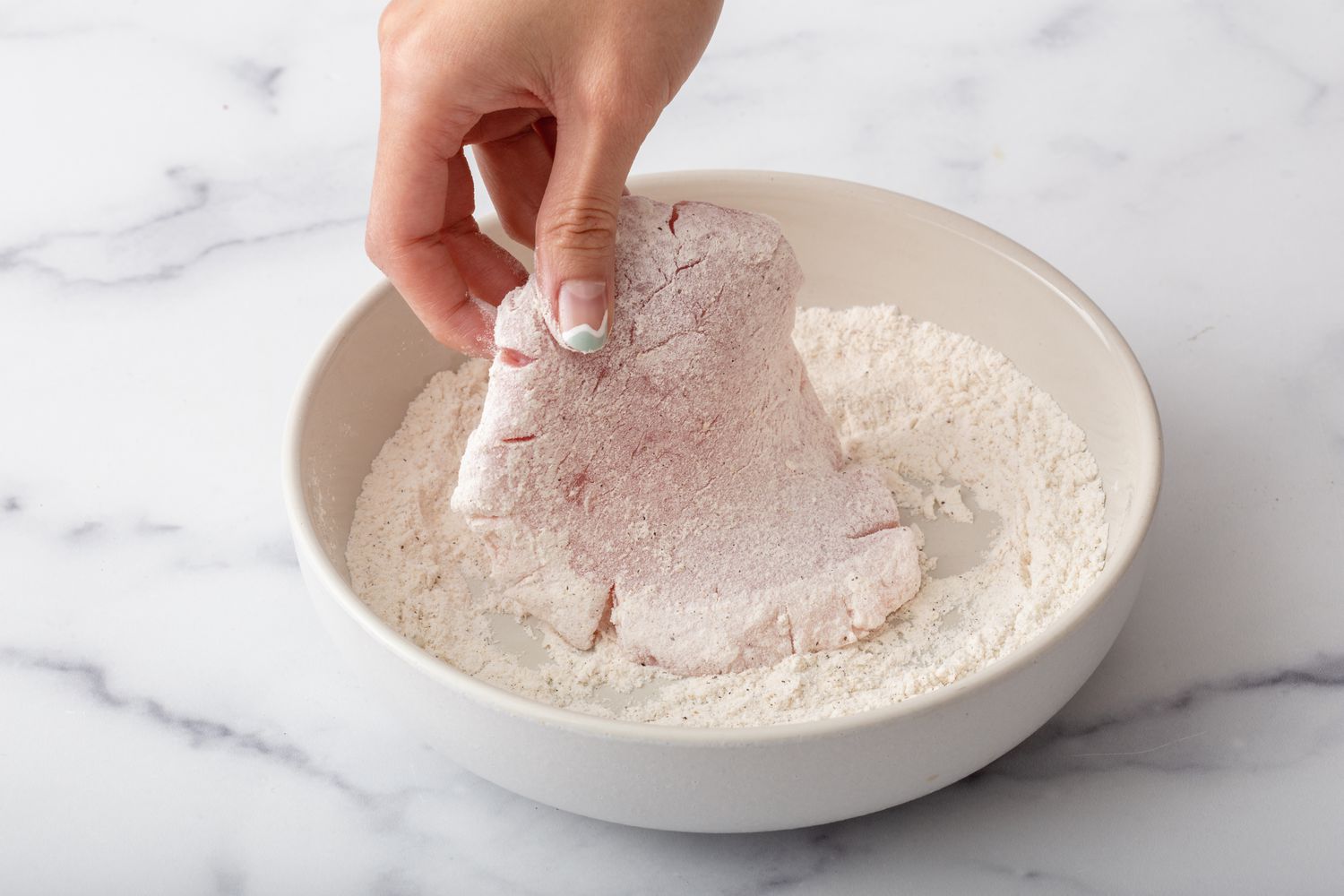 Coating pork cutlets in flour mixture.
