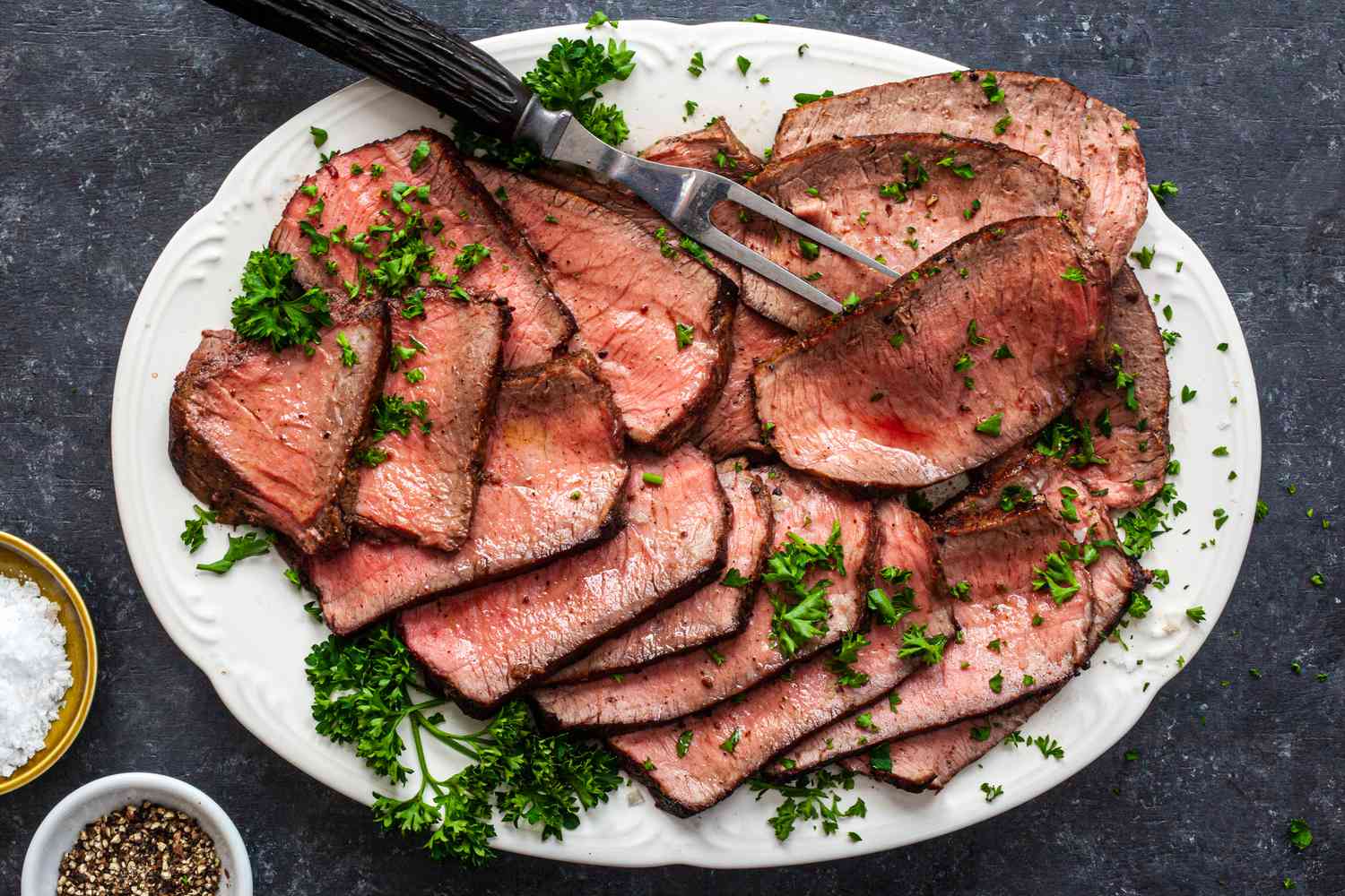 Overhead view of a platter of sliced pan fried steak.