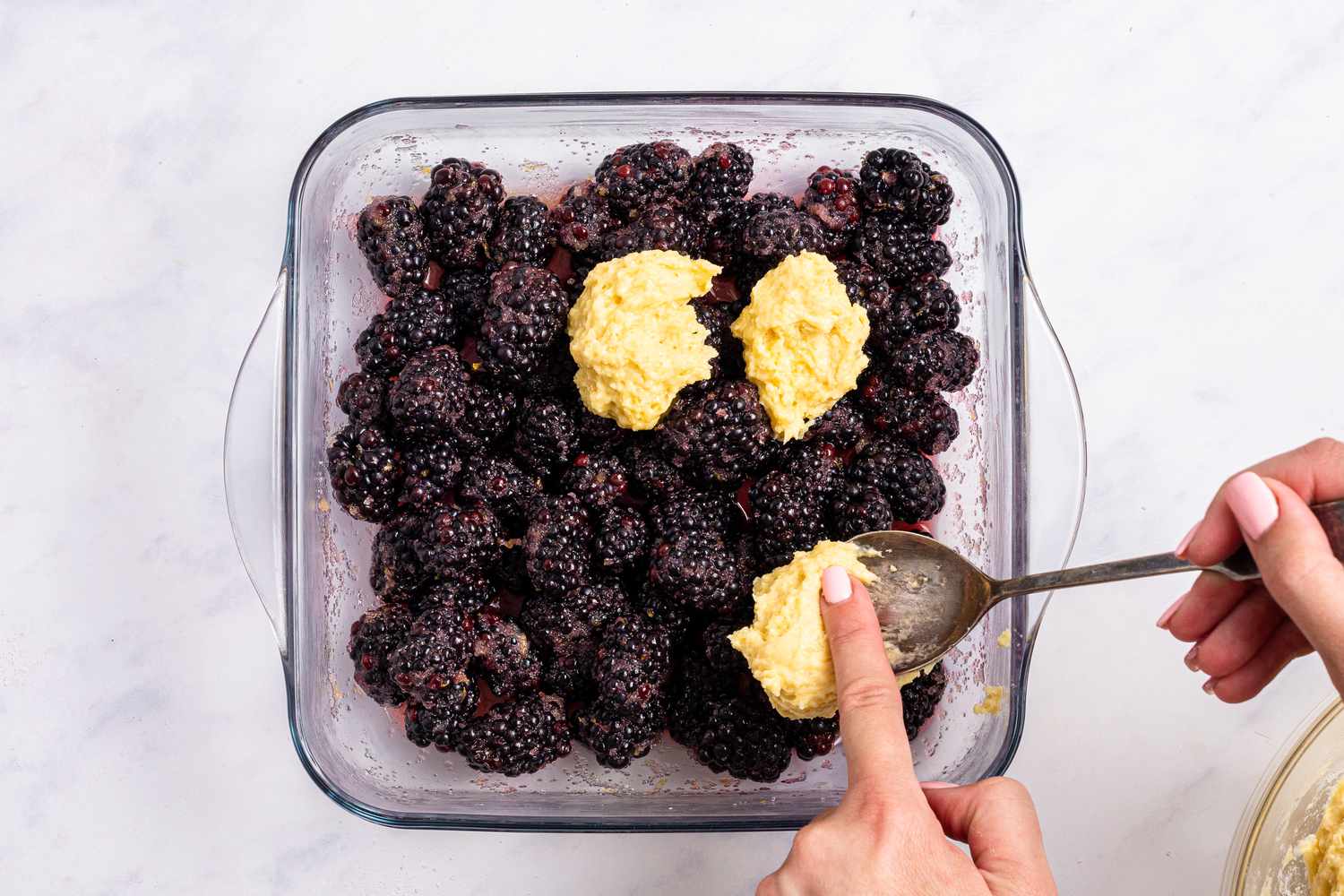 Dropping the topping by spoonfuls over the blackberry mixture to make blackberry cobbler recipe.