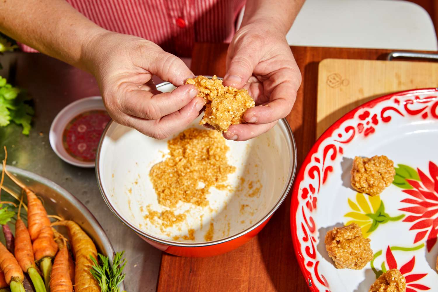 Hands forming matzo balls from a bowl and some already made on a platter