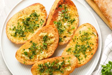 Slices of garlic bread garnished with herbs arranged on a plate