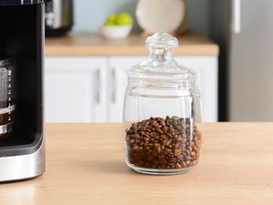 A glass jar with coffee beans on a wooden table