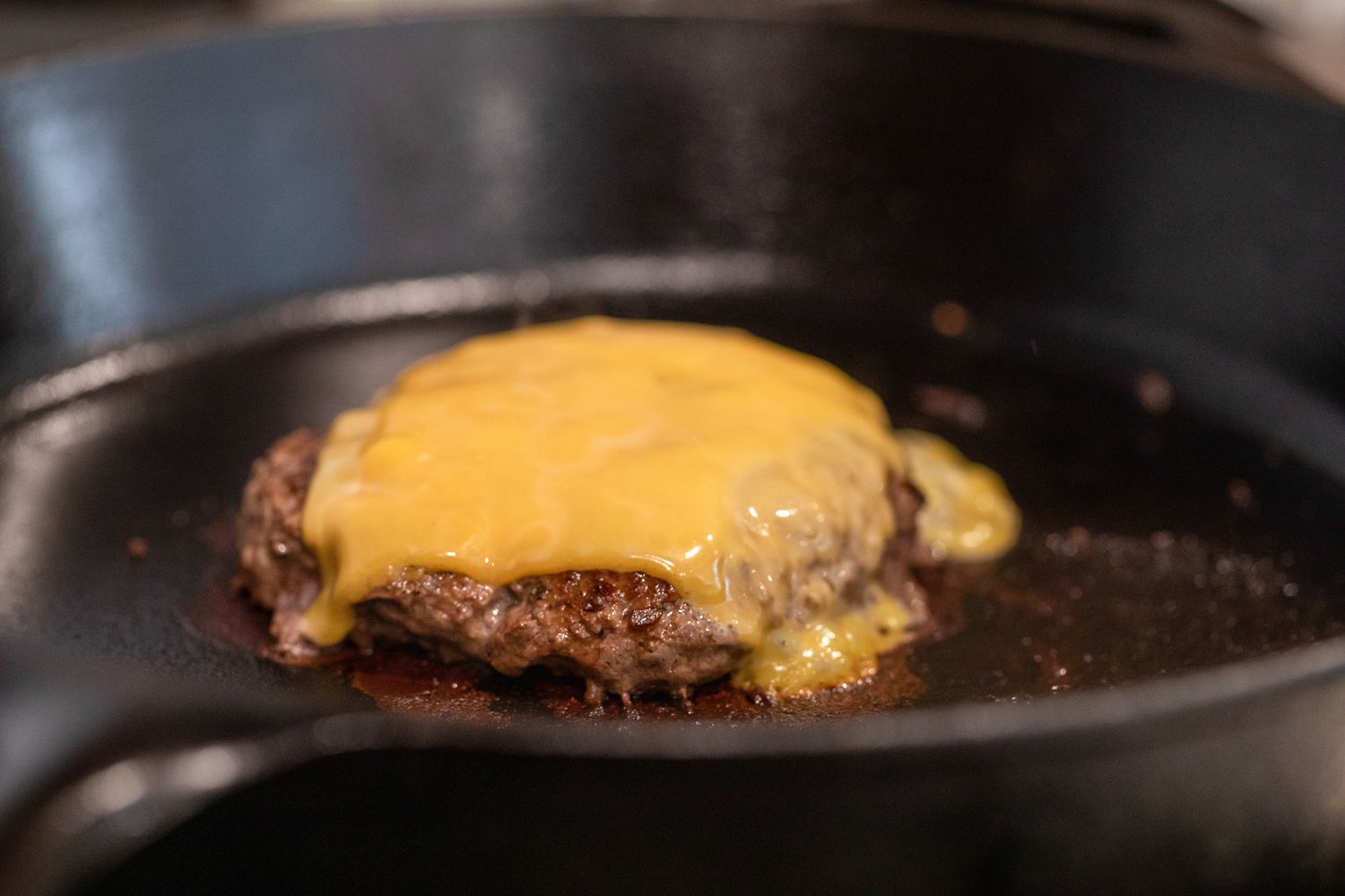 Cheese Melting on a Burger Patty on a Cast Iron Skillet for How to Make a Burger on the Stove