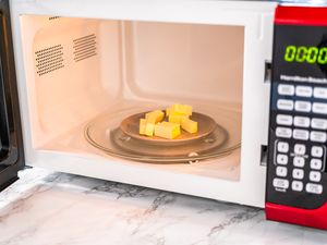 Butter cubes on a plate in a microwave oven with a marble countertop visible