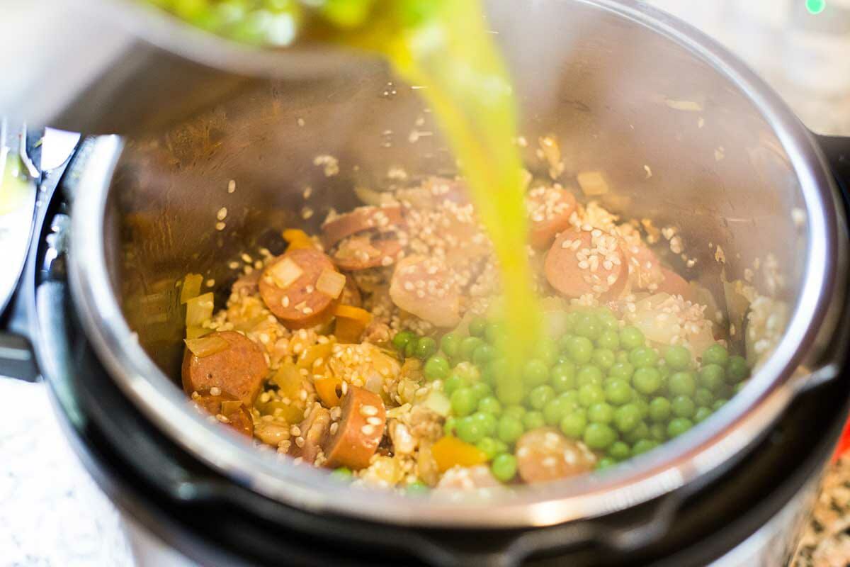 Pour the chicken broth, saffron, and peas over the other ingredients for making instant pot paella