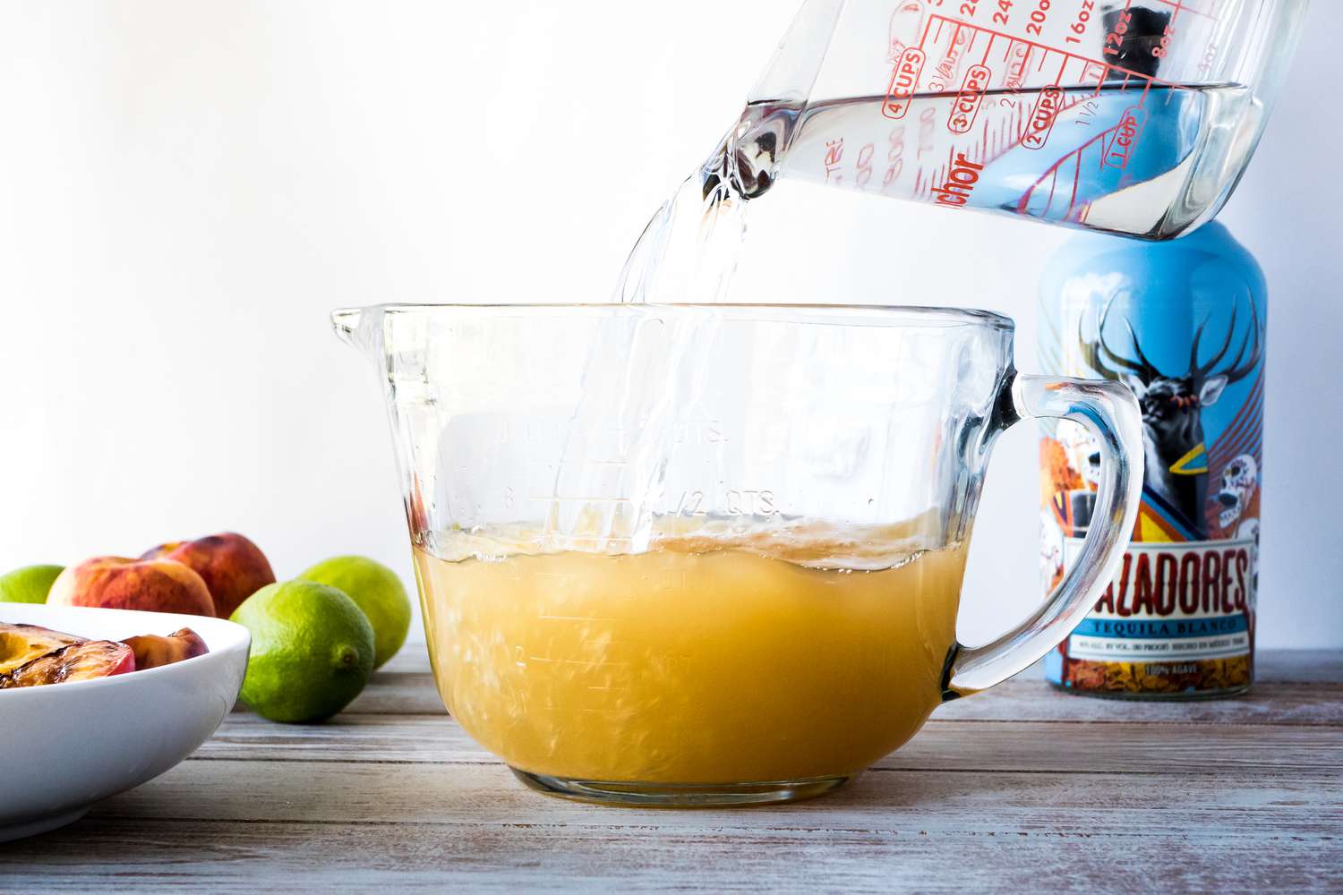 Pouring ingredients into a large spouted mixing bowl to make pitcher margaritas.