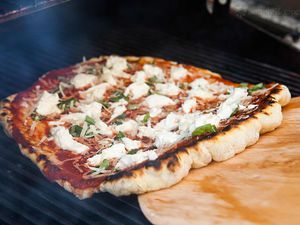Using a wooden peel to remove a pizza from the grill