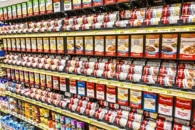 Store shelves stocked with various cans of Campbells soup
