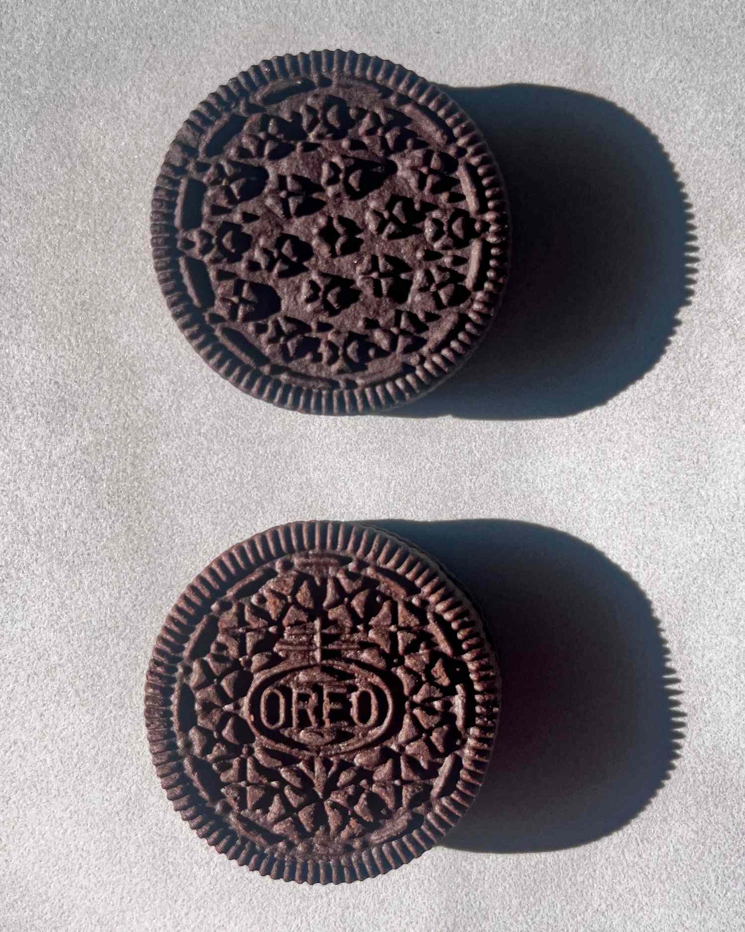Two chocolate sandwich cookies one with the Oreo brand logo and one with a generic design